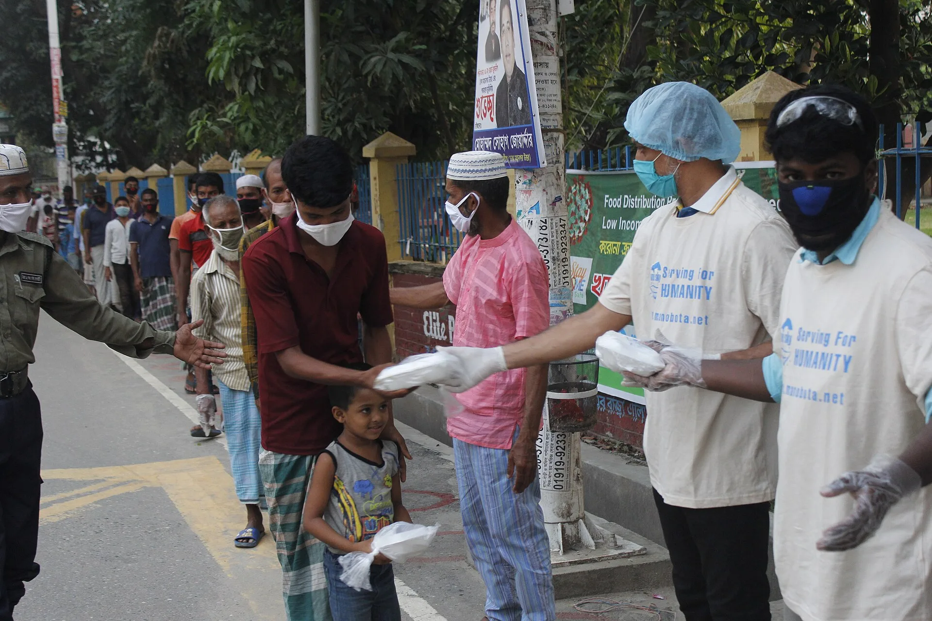 Volunteers handing out boxes of food at a community distribution site